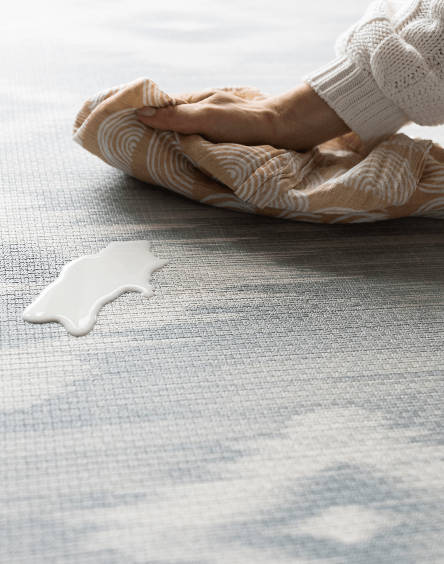 Milk spill being wipe away on Atlas blue and beige tumbling mat by totter and tumble for easy cleaning in the home