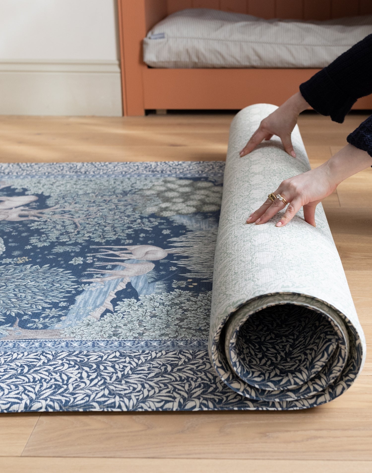 Unrolling a one-piece luxury playmat from Totter + Tumble with woodland animal and floral motifs - decorative, easy-to-clean and perfect for warm maximalist interiors.