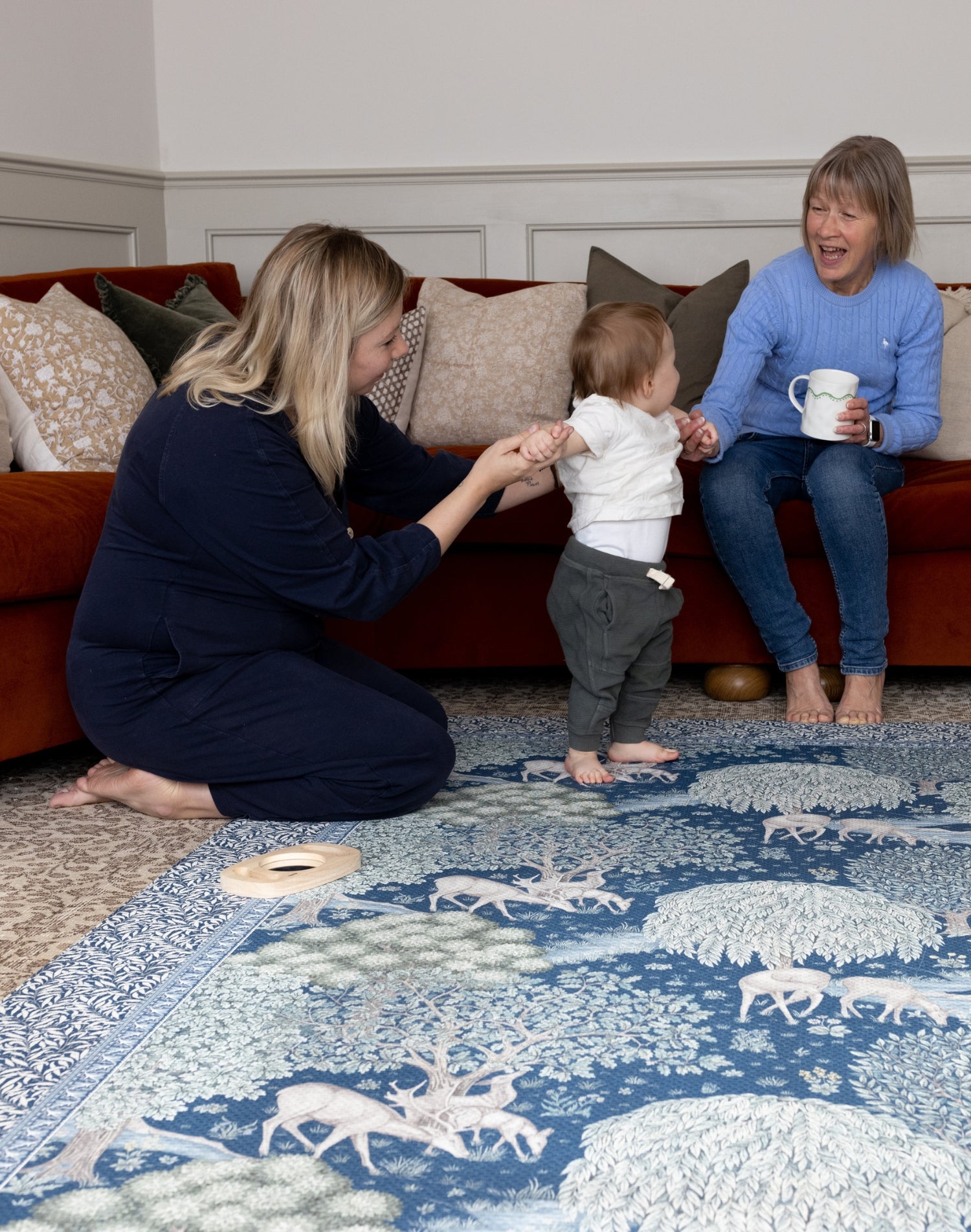A family play together on a Morris & Co. padded play mat - modern classic interiors meet sustainable family home design.