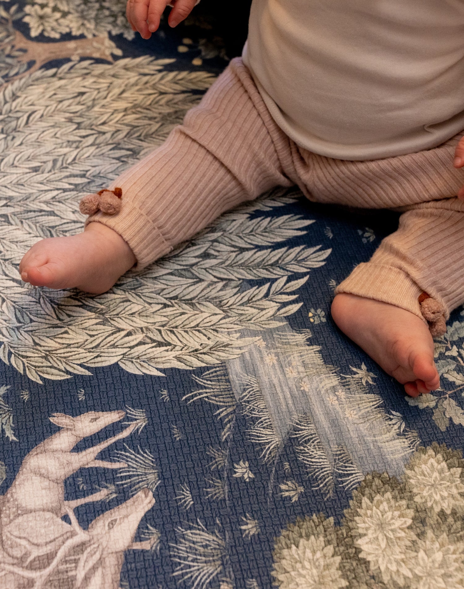 Close-up of baby’s legs on a Totter + Tumble woodland play mat; a safe foam play mat for lovers of premium baby products.