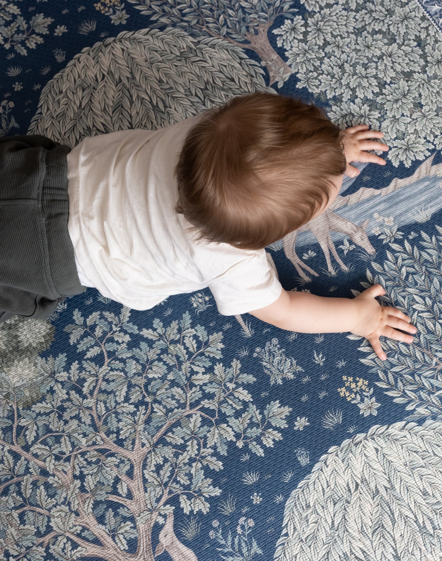 Bird’s-eye view of a baby exploring a William Morris decorative play mat - functional nursery decor meets elegant baby room.