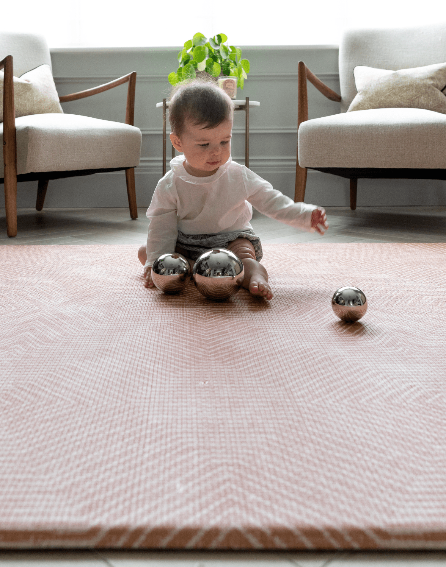 Little girl plays with sensory toys on the Totter and Tumble Tapis designed for safe play in the home