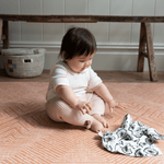 Baby enjoys playing on thick padded floor mat with a sensory black and white muslin
