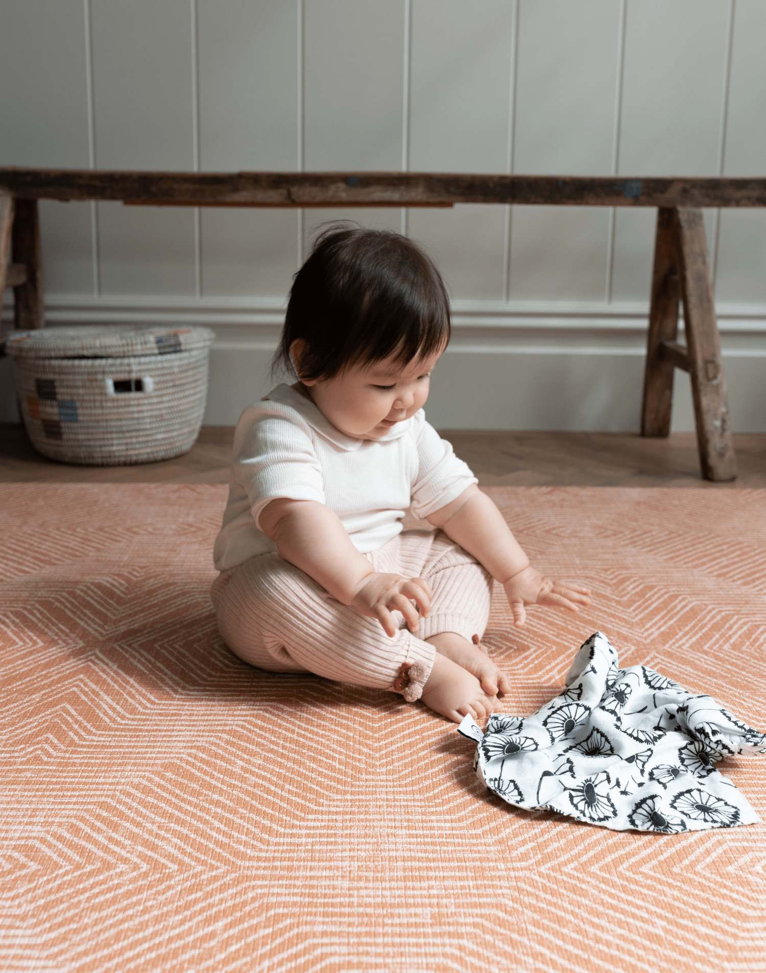 Baby enjoys playing on thick padded floor mat with a sensory black and white muslin
