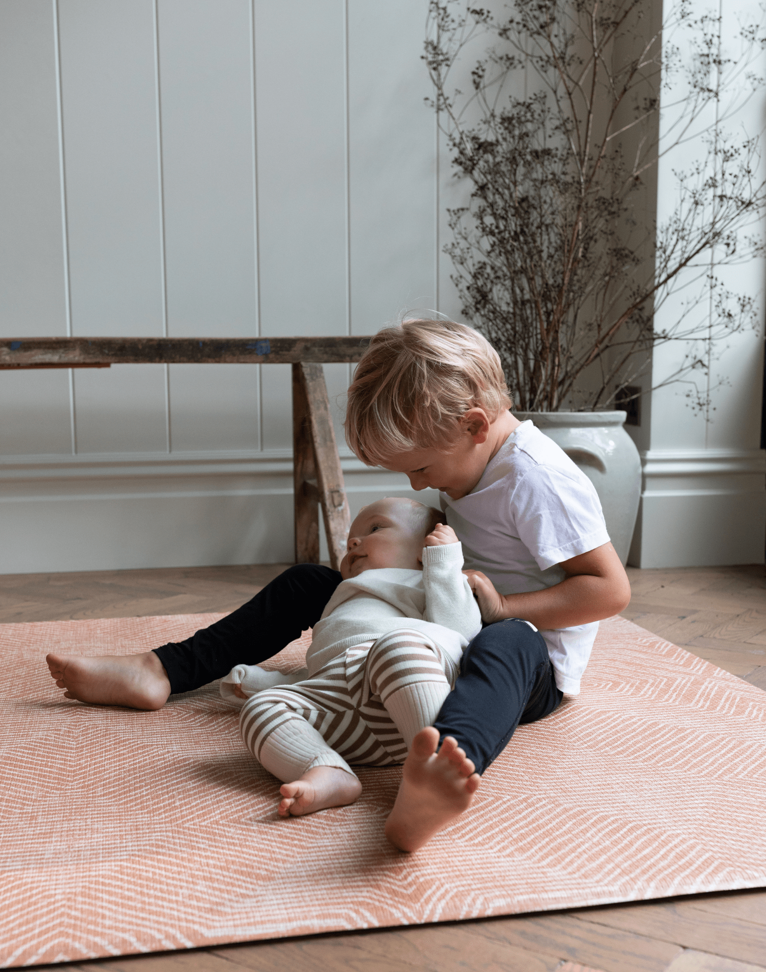 Baby and toddler enjoy floor play on padded foam mat with stylish orange design