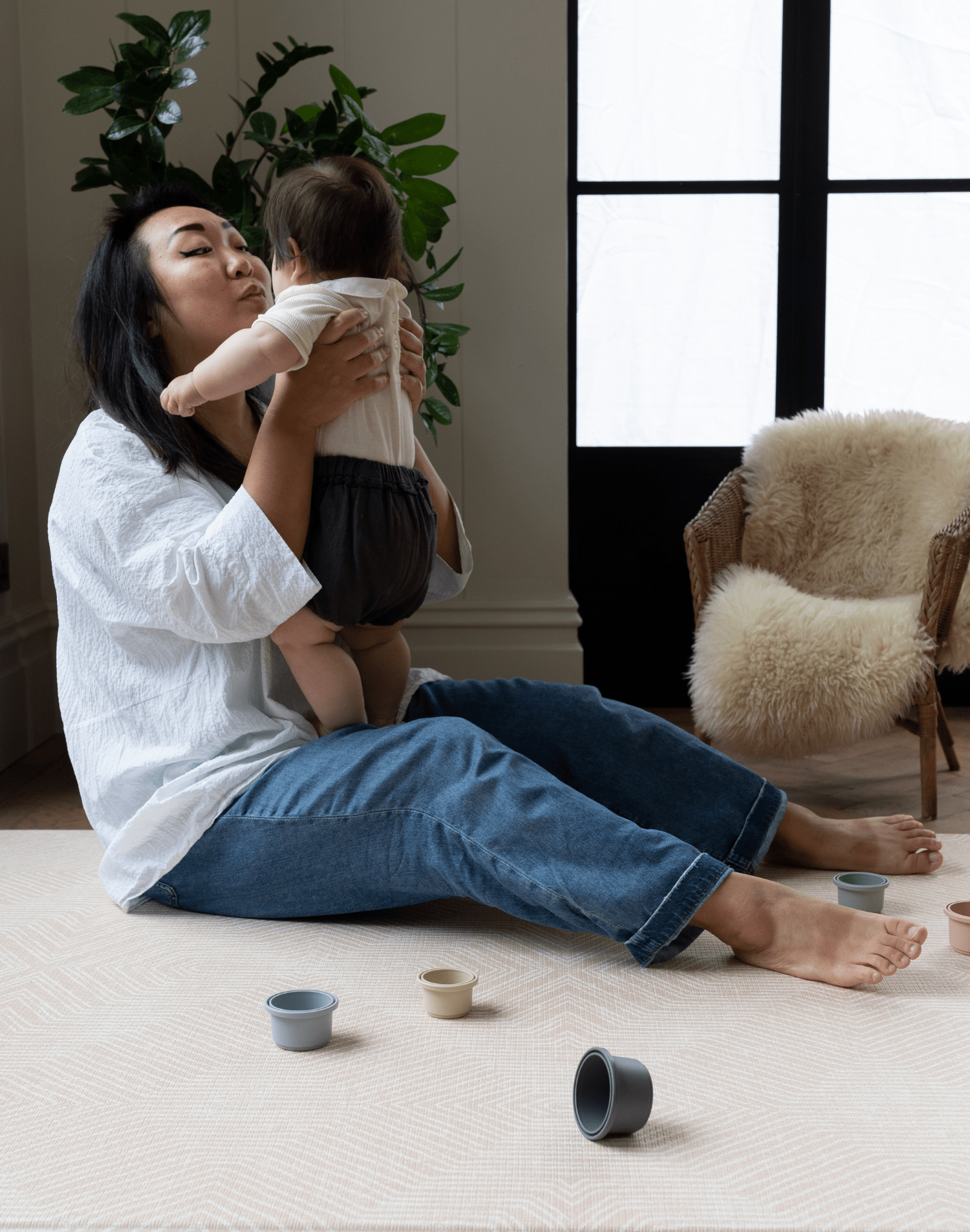 Lady holds baby sitting on pink foam baby mat making living more comfortable