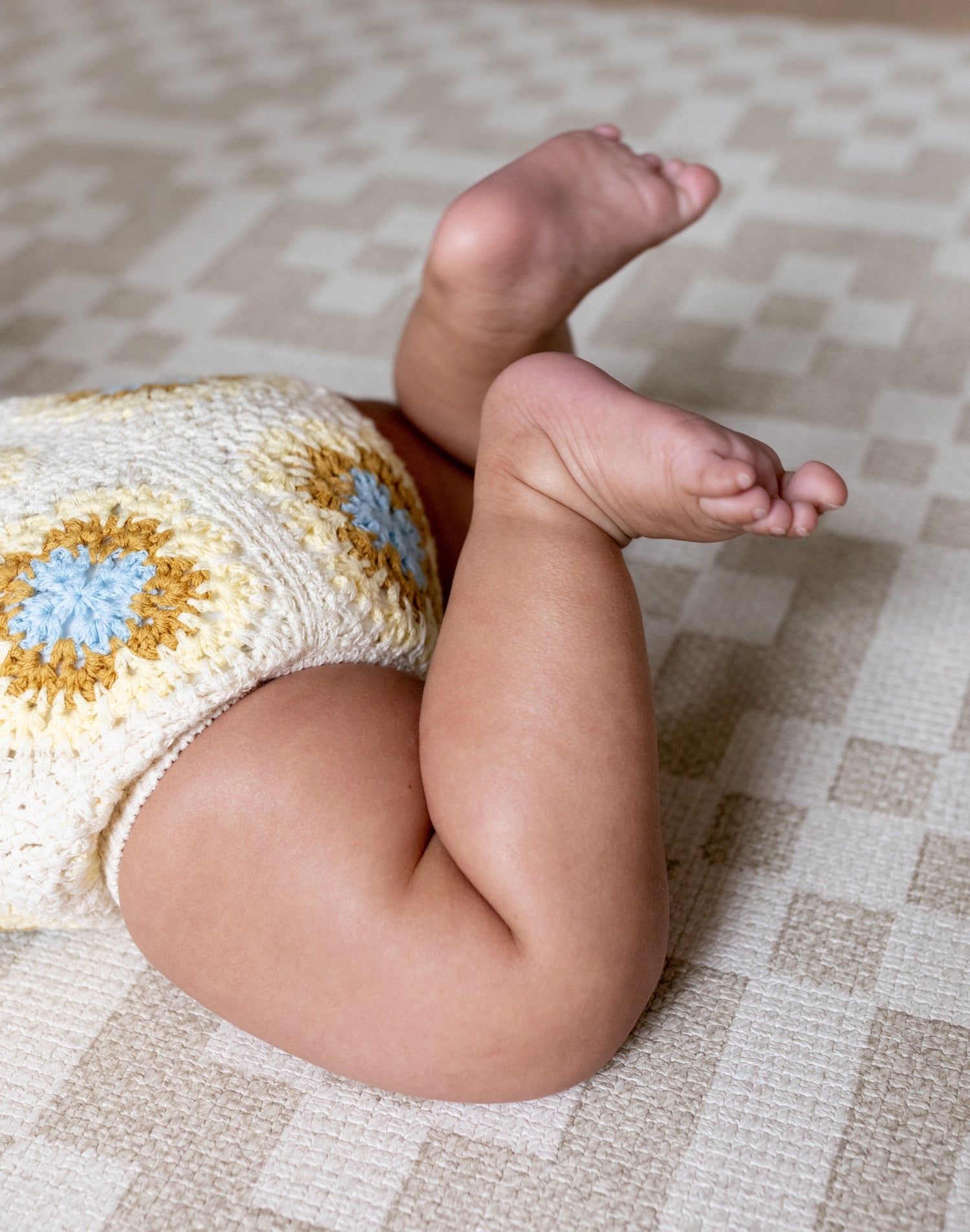 Close-up of crawling baby on The Holbein, a soft checked crawling mat with calming colours for modern nurseries.