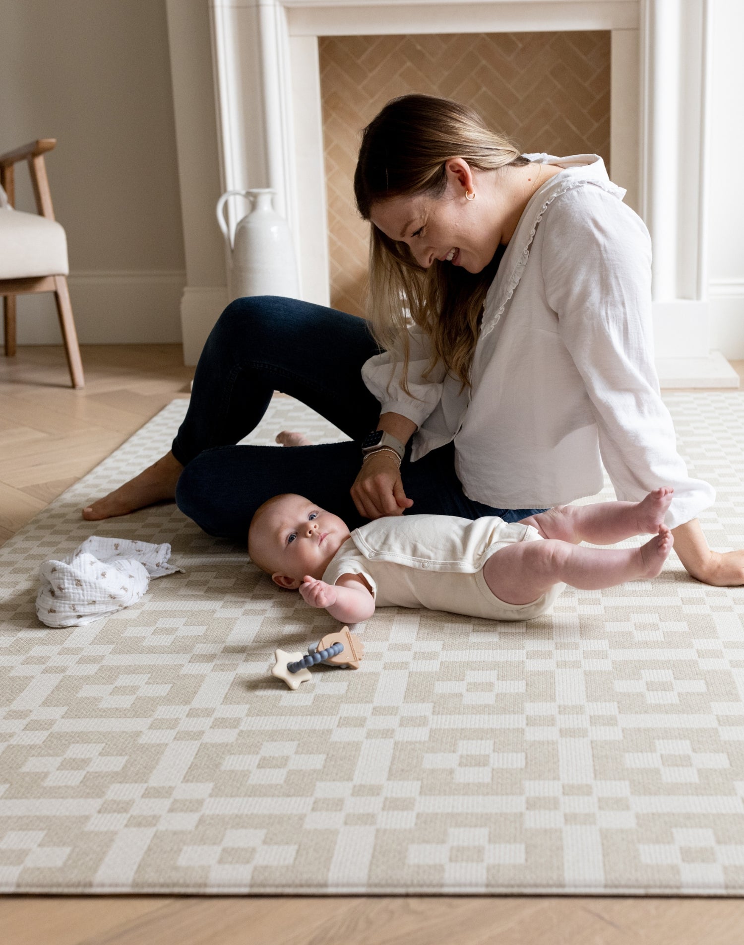Mother and baby bond on The Holbein, a wipeable tummy time mat in a soft stone and sand coloured check pattern.