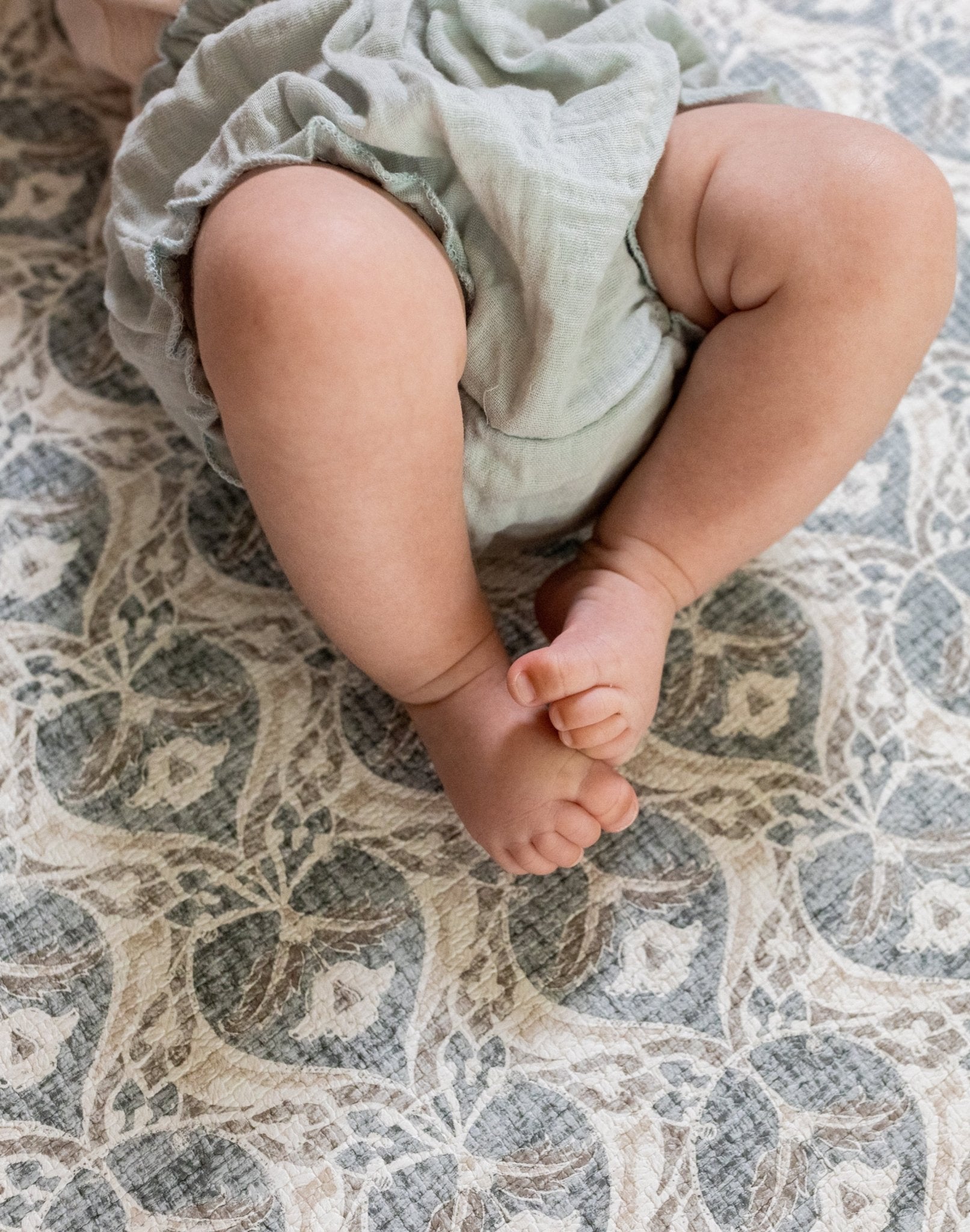 Baby's feet lying on a soft grey textured playmat