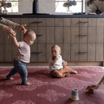 Padded large playmat in vibrant red design in kitchen with babies and their mother enjoying floortime play in comfort