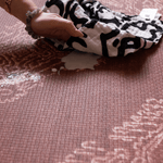 Hand wipes milk spillage on wipeable playmat with sealed surface to ensure cleaning is simple