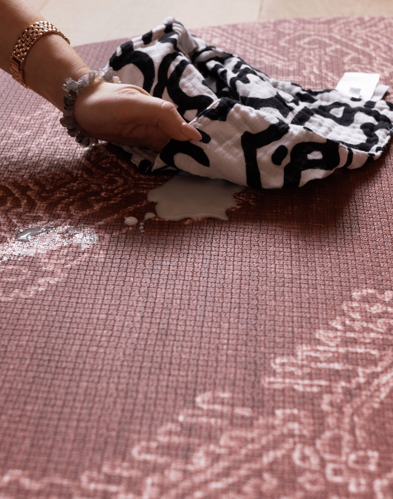 Hand wipes milk spillage on wipeable playmat with sealed surface to ensure cleaning is simple