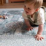 Happy toddler crawls on a Totter + Tumble luxury padded play mat in a William Morris botanical design. It is a a non-toxic, stylish addition for any modern nursery.