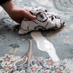Wiping down a durable Totter + Tumble non-toxic foam play mat - easy-to-clean surface with William Morris floral heritage print in the Owl & Willow design, ideal for practical parenting with style.