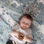 Smiling baby on a Totter + Tumble non-toxic play mat with woodland animal prints - the ultimate in luxury baby products and soft tummy time mats.