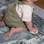Side view of toddler exploring a decorative play mat with woodland and floral motifs - a premium foam mat for safe and chic play spaces.