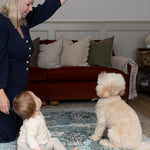 Parent and baby interact with family dog on a luxury padded play mat - a safe and stylish baby space with timeless Morris & Co. woodland prints.