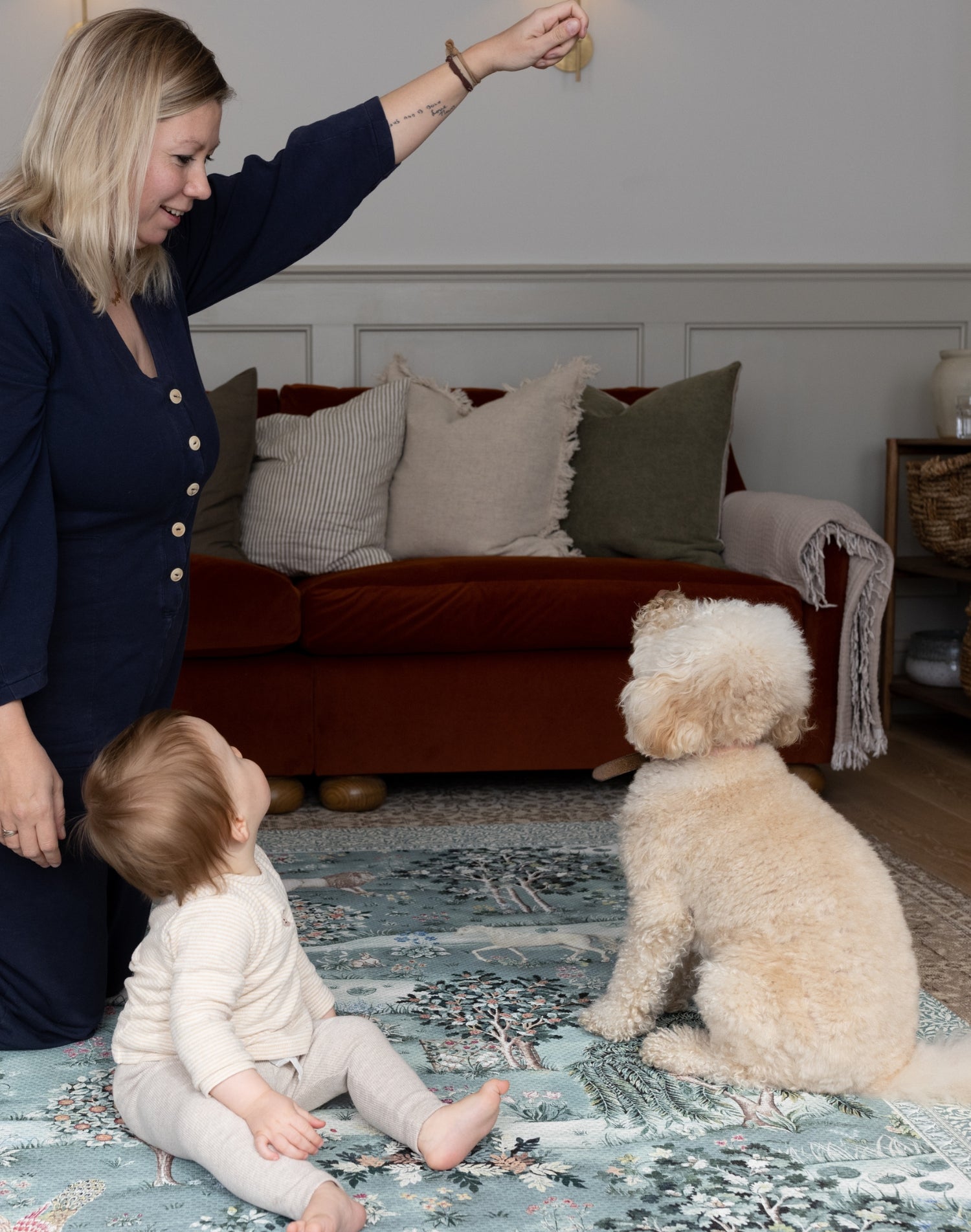 Parent and baby interact with family dog on a luxury padded play mat - a safe and stylish baby space with timeless Morris & Co. woodland prints.