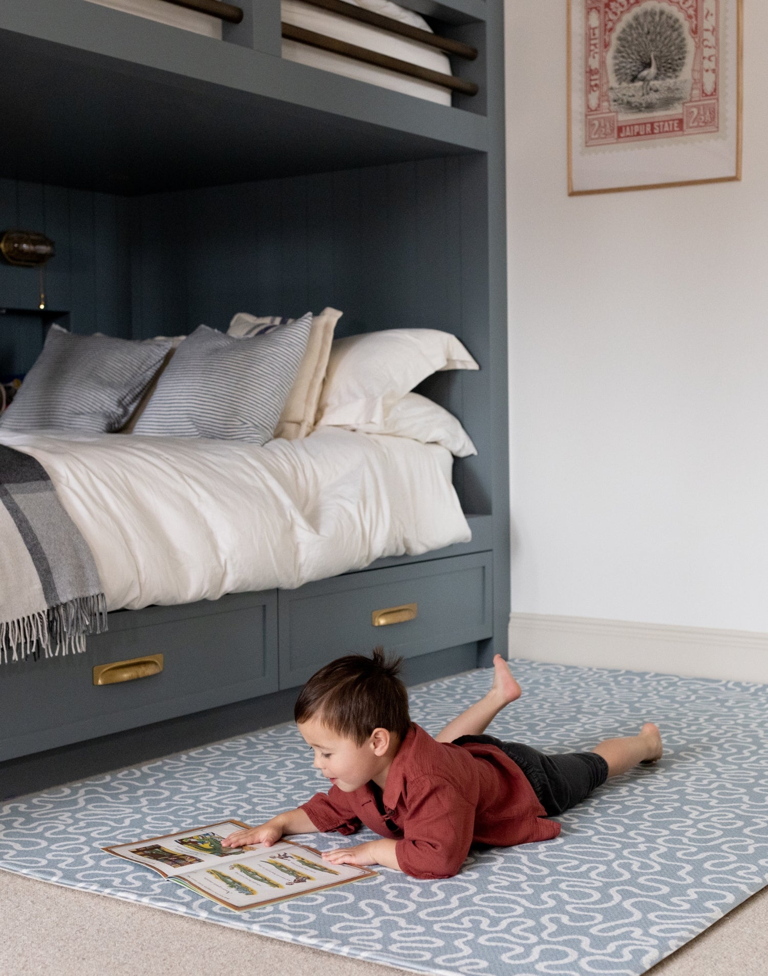 Child reading on a Totter + Tumble play mat, a soft and safe playmat for cosy corners and quiet play in small spaces.
