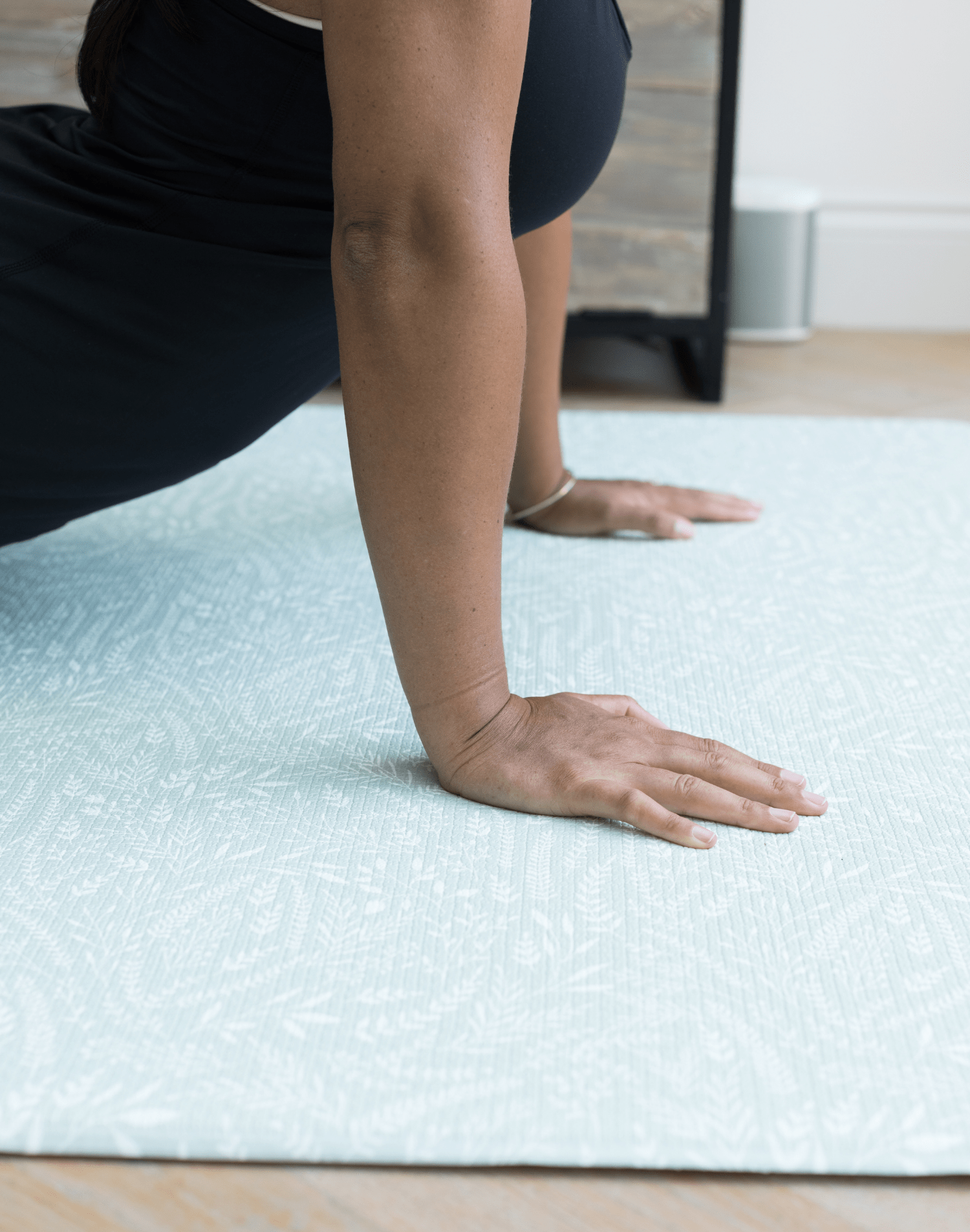 Lady is supported using the exercise mat by Totter and Tumble with a modern botanical design
