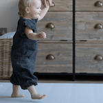 Toddler holds adults hand and walks across textured memory foam playmat