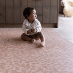 Baby sitting unaided on textured play mat thick memory foam design for support and protection on the floor soft orange play mat colour that blends seamlessly into modern family living spaces
