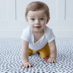 Little baby crawls across crawling mat with textured surface for traction while moving