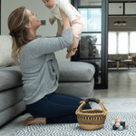 lady holds her baby while playing on the large round baby mat with a modern design