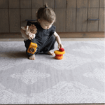 Toddler stacks toys on stable grey play mat with textured design for support and memory foam for protection on tiled flooring large size creates a dedicated play area on the floor