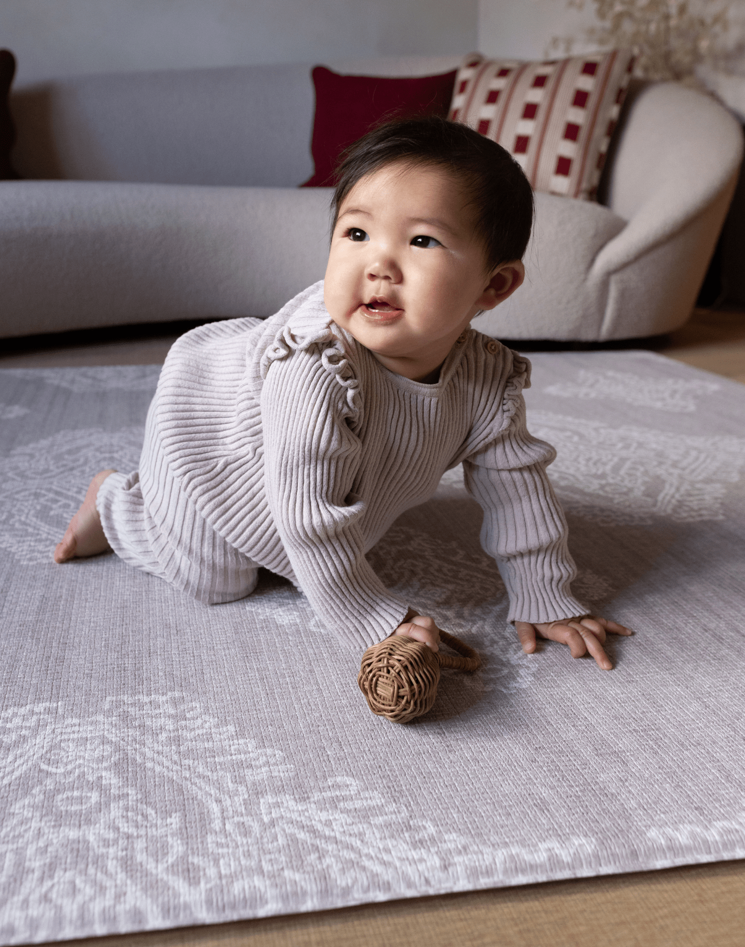 Baby girl crawls across the large grey crawling mat by totter and tumble the sepi designed to look like a rug with the practical features you need from a playmat a no compromise design perfect for modern family homes