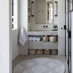 Large round waterproof playmat unrolled in bathroom space to add protection on the floor and allow for comfier changing time