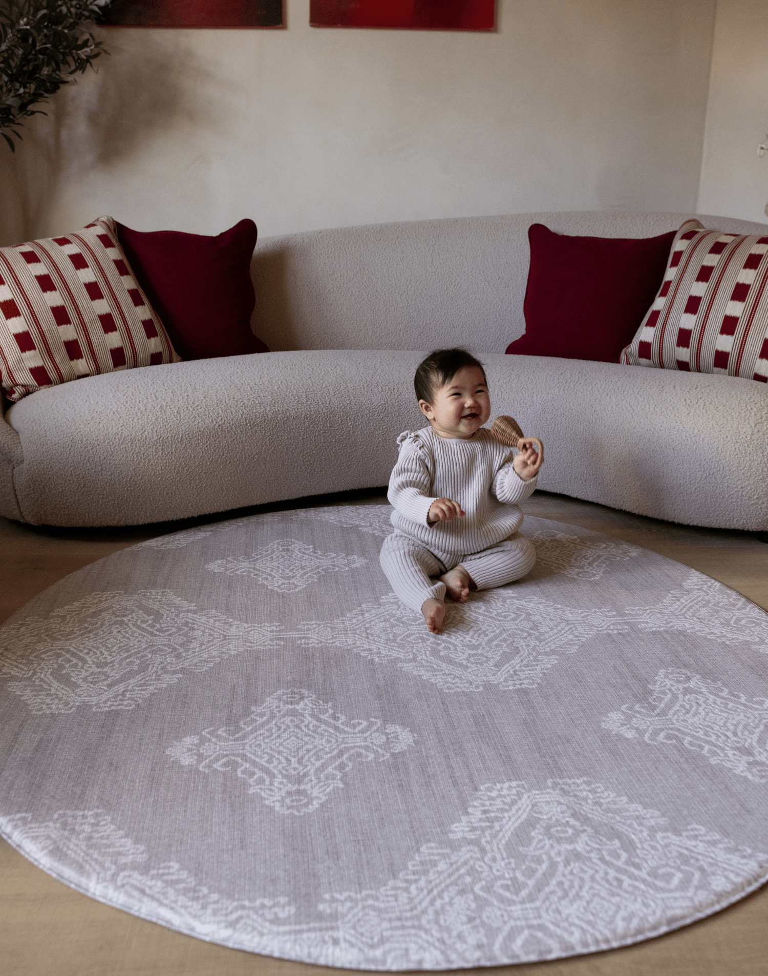 Baby girl sits on extra large round playmat a grey design looks like a rug but has the practical elements you need from a play mat textural batik effect and a subtle grey tone looks beautiful in modern interiors
