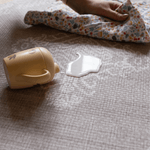 Hand wipes up milk spill on sealed waterproof playmat designed to be easy to clean a practical playmat for busy family homes