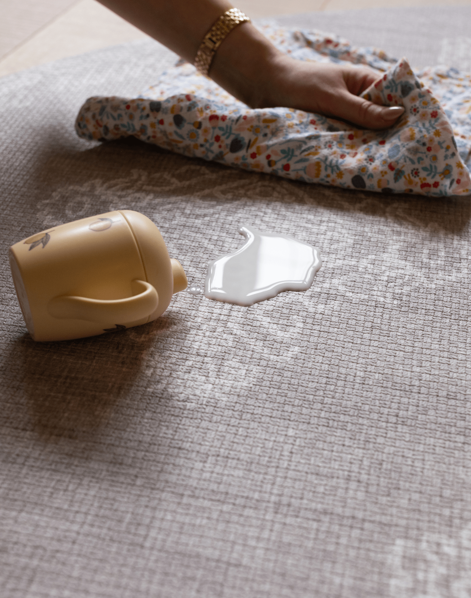 Hand wipes up milk spill on sealed waterproof playmat designed to be easy to clean a practical playmat for busy family homes