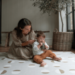 Lady and child sit together on tan one piece play mat with a modern design that looks great in modern living space