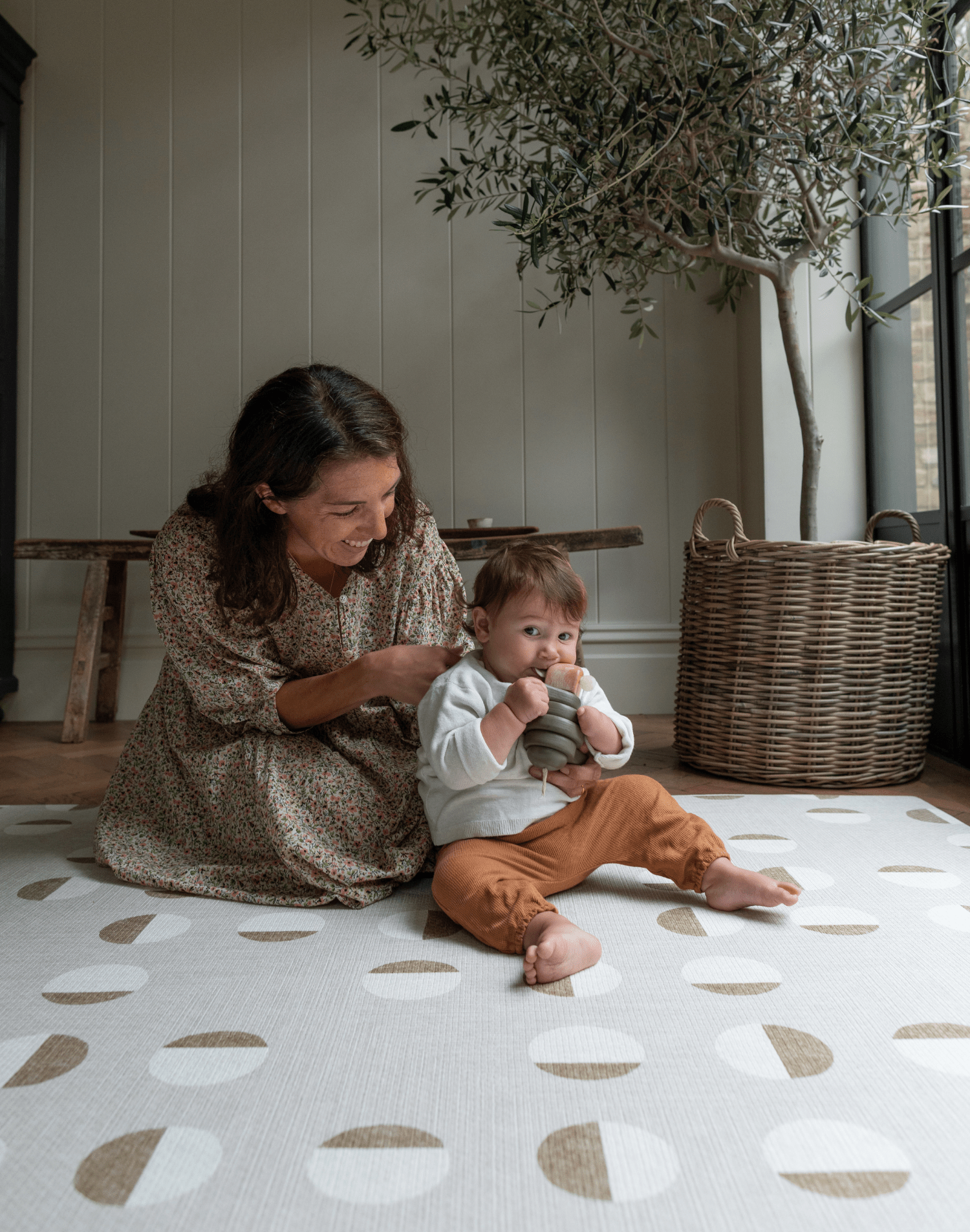 Lady and child sit together on tan one piece play mat with a modern design that looks great in modern living space