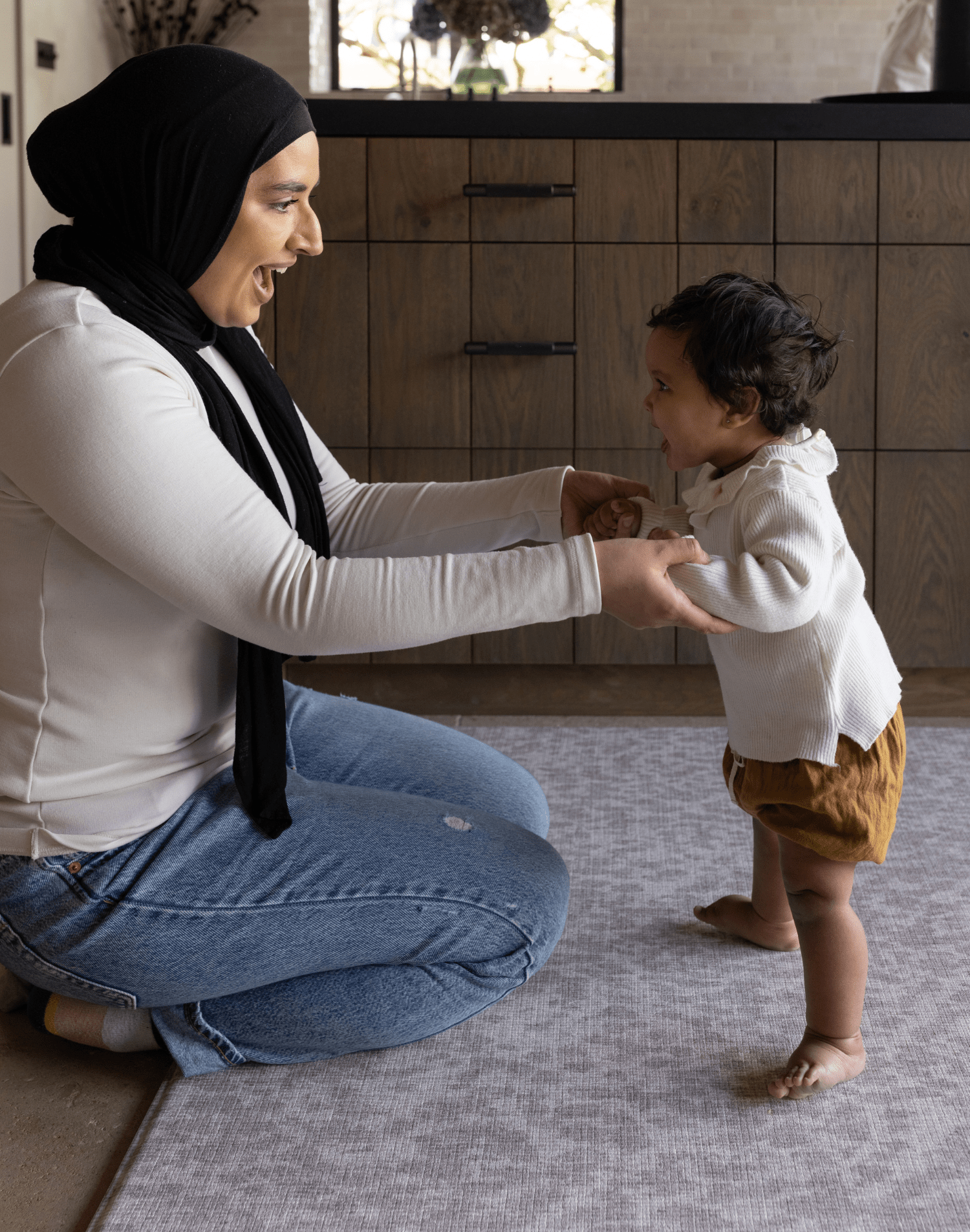Mum and baby enjoy floor time together on the comfortable grey playmat by totter and tumble the sunda with delicate animal print play mat design that looks stylish in the family home with luxury memory to support the whole family