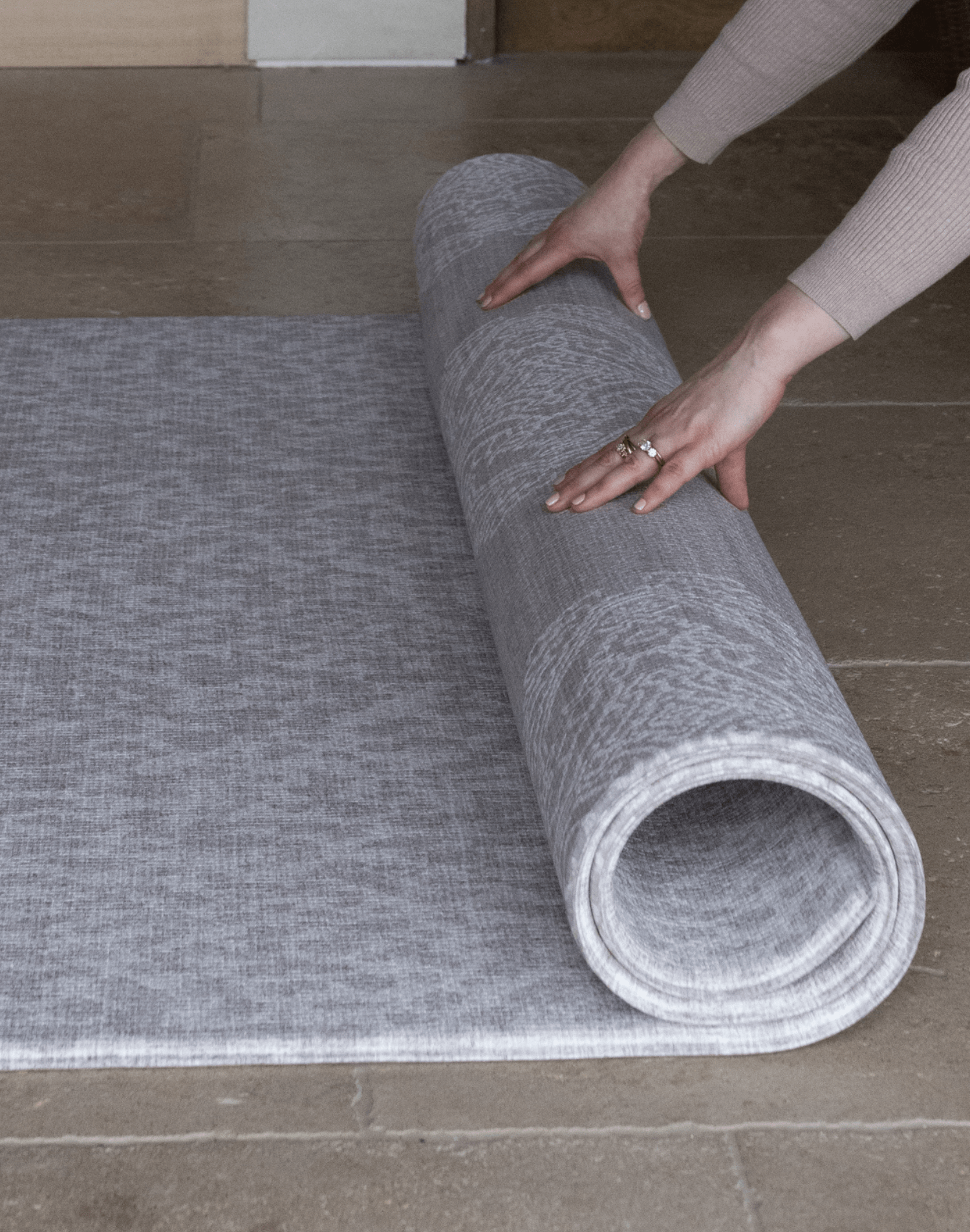 Hands roll out the reversible grey play mat by totter and tumble with two complementary grey designs for family homes and thick memory foam for comfy floor time activities