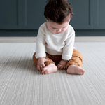 Baby sitting on Tan and beige ombre baby play mat sits stylishly in modern family homes