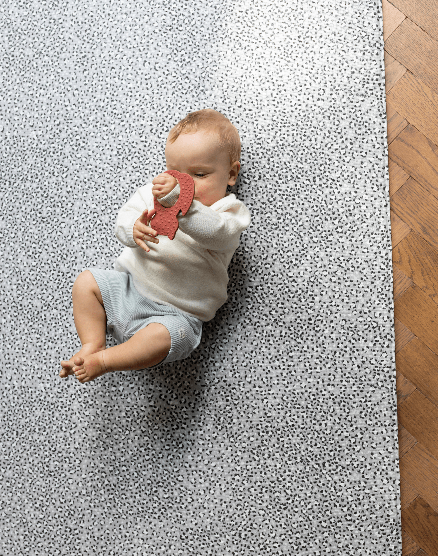 Baby plays on soft foam mat with textured teething toy
