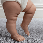 Baby practices standing on foam mat with textured surface for added support