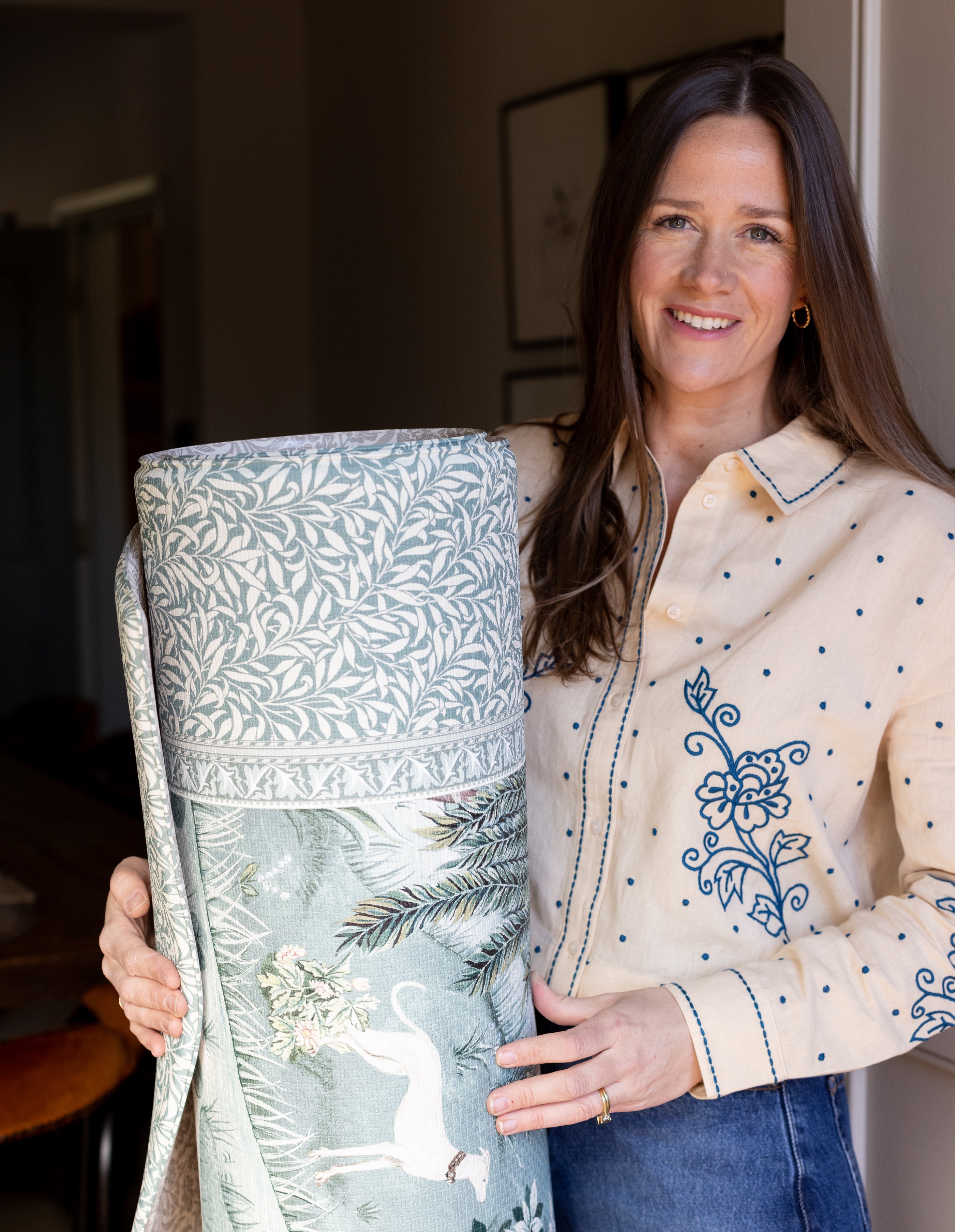 Susie Stubbs founder of Totter + Tumble holding a rolle dup playmat in a sage green Morris & Co design