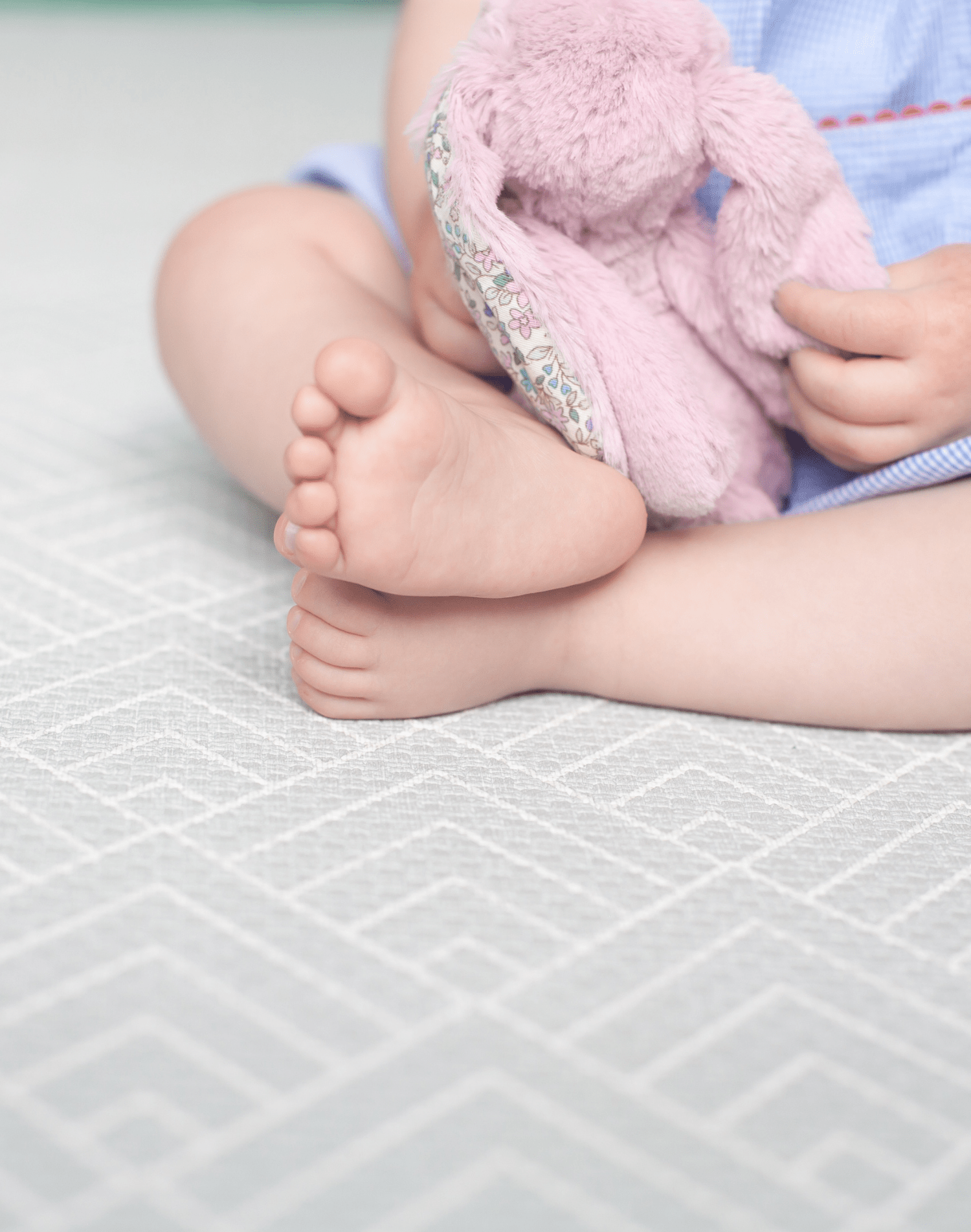 Baby sits safely on non toxic play mat designed from birth with a gentle grey design