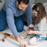 Father and daughter play on padded play mat with protective foam design and modern grey pattern