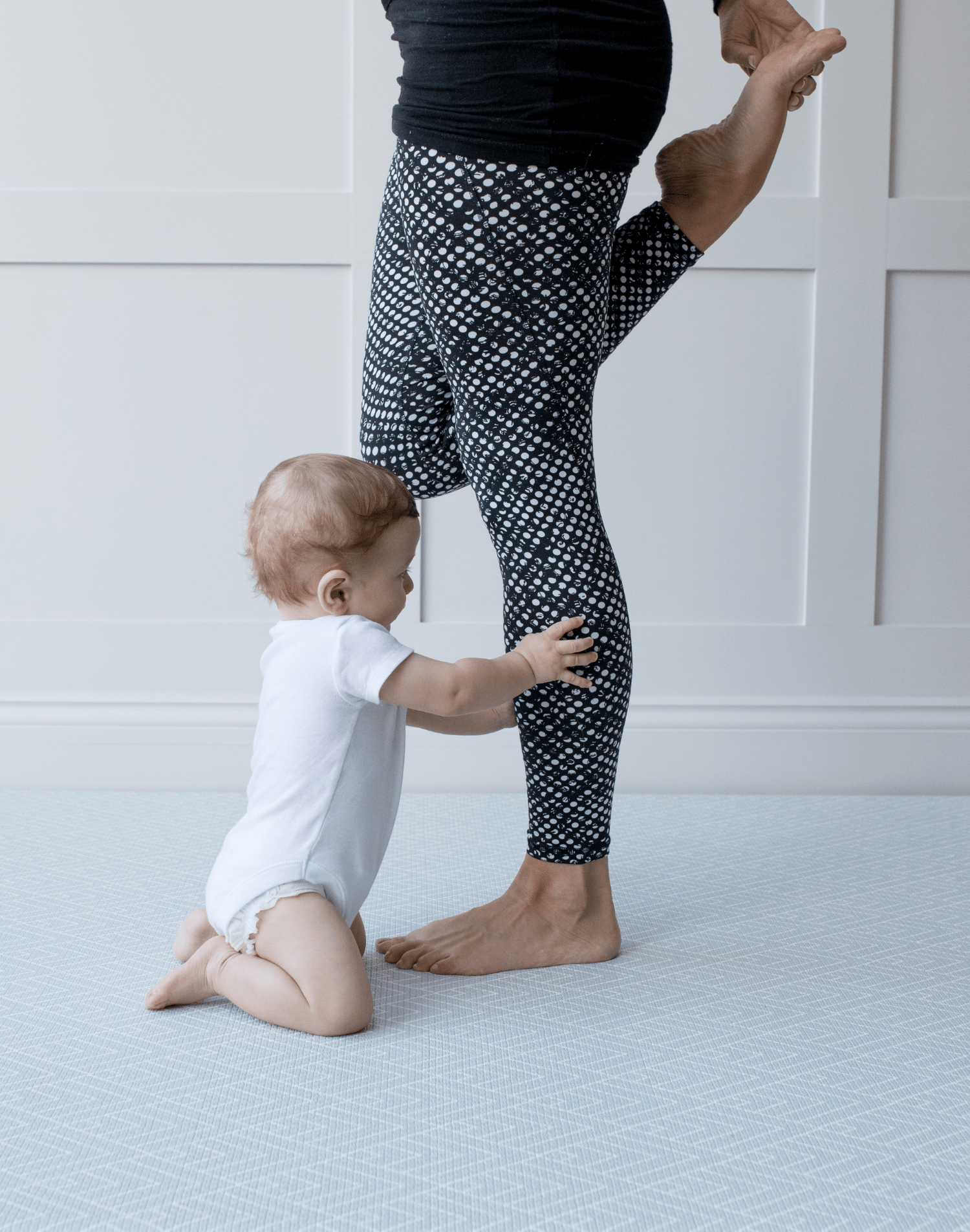 Baby reaches for mums legs on extra large yoga mat with wanderer design by totter and tumble