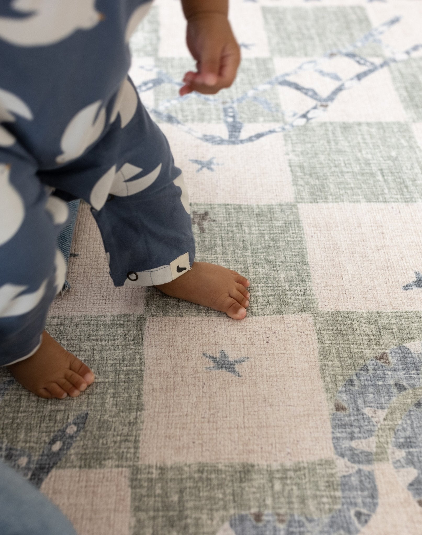 Child's feet on a checkered first movement shock absorbing baby play mat