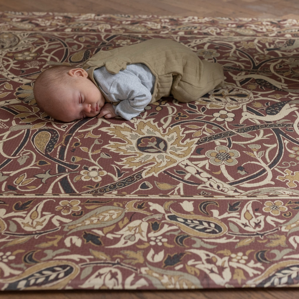 A child lies on a checkered green and beige playmat