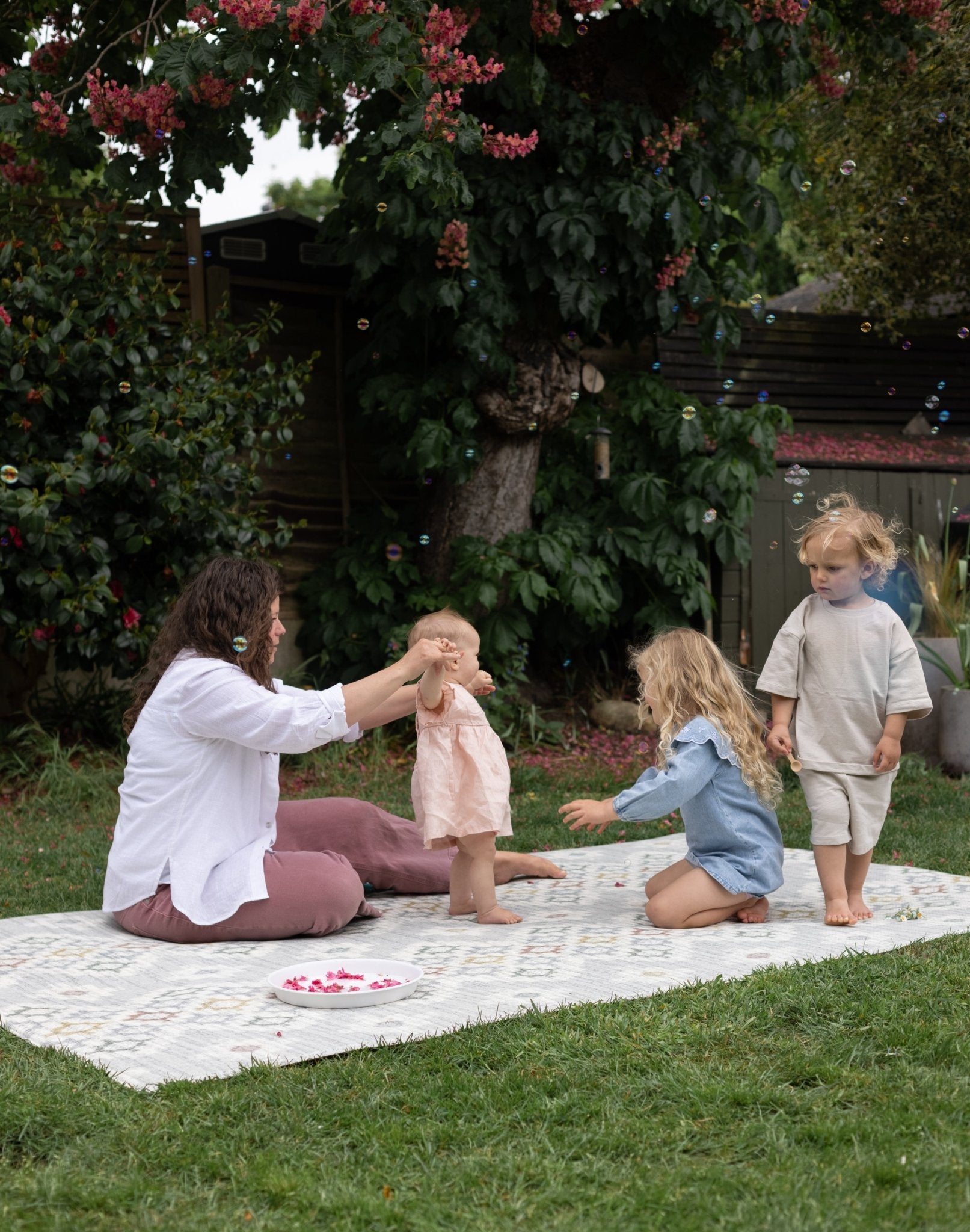 Woman and children playing outdoors on a memory foam kids playmat.