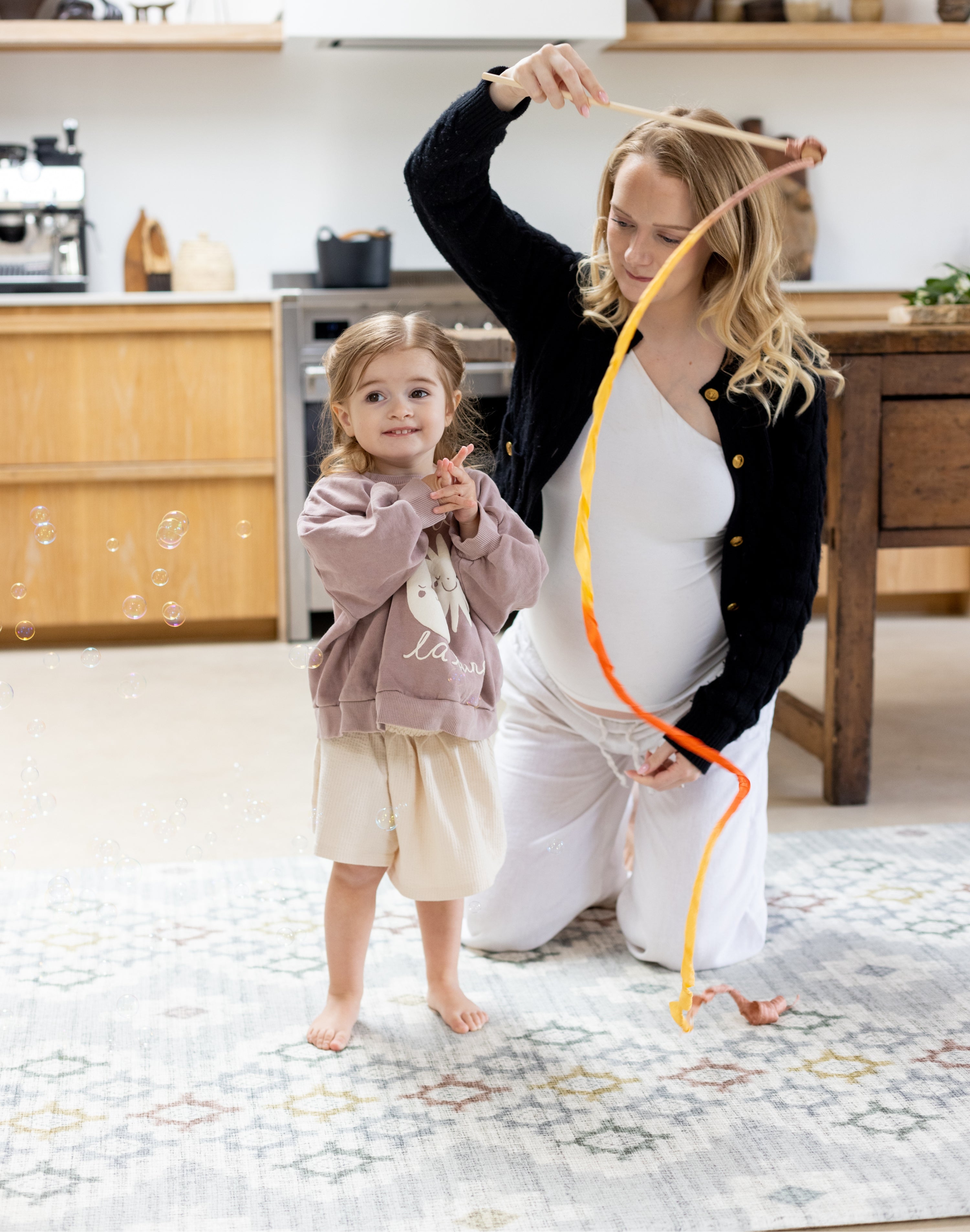 Woman and child playing on a designer baby play mat that matches home decor