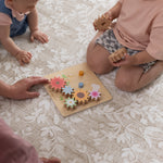 Two children playing with a wooden toy on a safe cushioned play mat for crawling